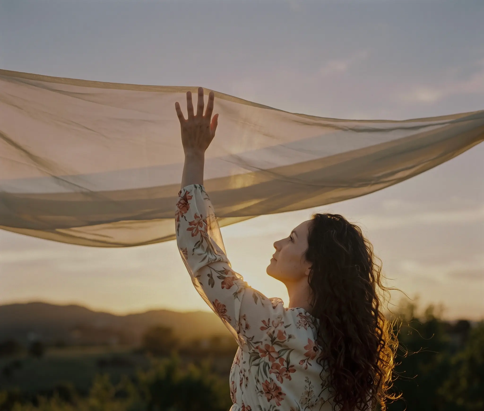 Mujer al atardecer sosteniendo al viento un pañuelo
